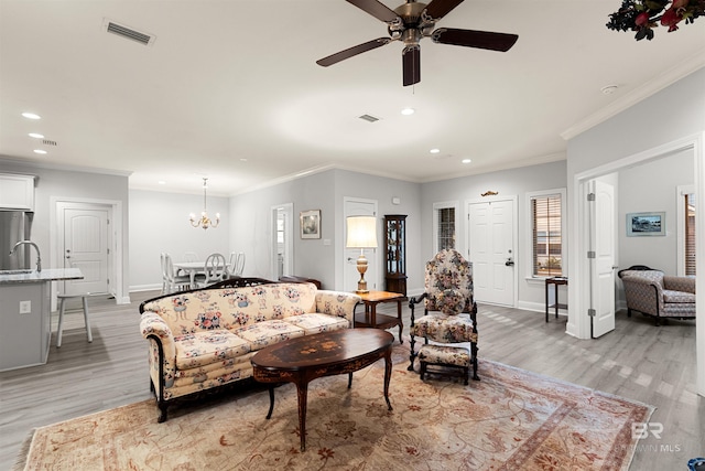 living room with crown molding, sink, ceiling fan with notable chandelier, and light hardwood / wood-style floors