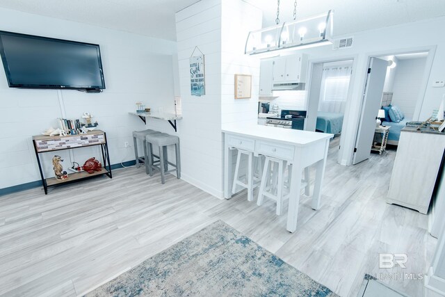 kitchen with pendant lighting, light countertops, visible vents, white cabinets, and stainless steel range oven