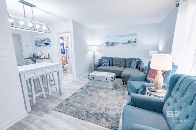 living area featuring baseboards, light wood finished floors, and an inviting chandelier