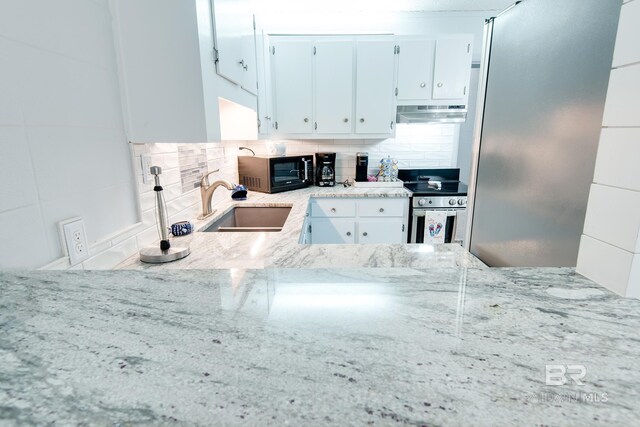 kitchen featuring stainless steel electric stove, tasteful backsplash, a sink, black microwave, and extractor fan