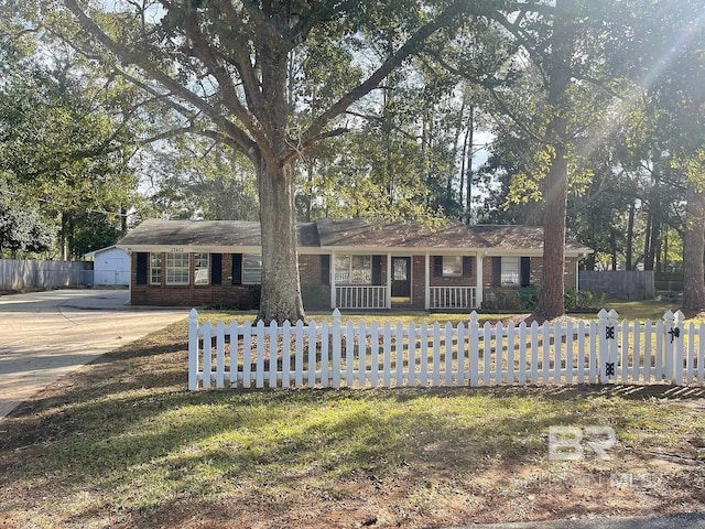 ranch-style house with a fenced front yard, brick siding, and a porch