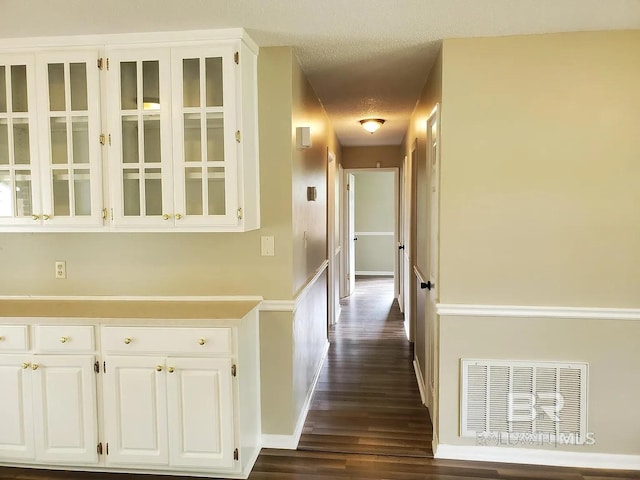 hall with dark wood-style flooring, baseboards, and a textured ceiling