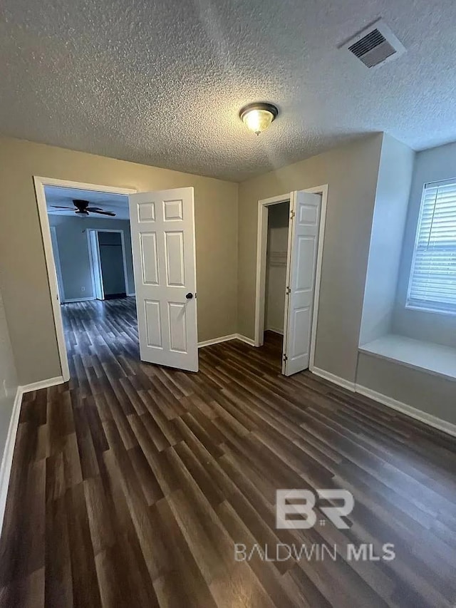 unfurnished bedroom with baseboards, dark wood finished floors, a textured ceiling, and a closet