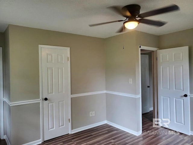 unfurnished bedroom with dark wood-type flooring, baseboards, and ceiling fan