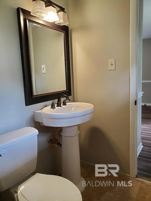 bathroom with toilet, baseboards, and tile patterned flooring