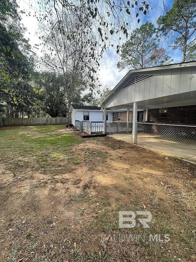 view of yard with fence, concrete driveway, and an attached carport