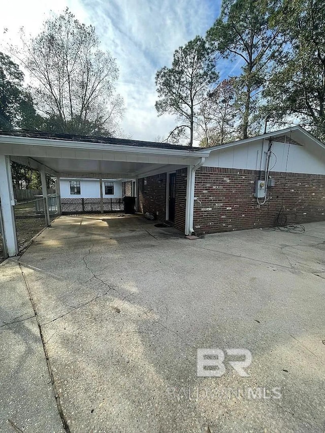 view of parking / parking lot with driveway, a carport, and fence