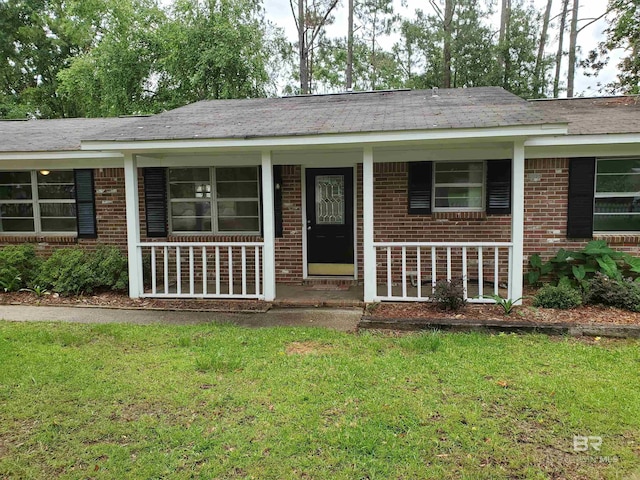ranch-style house featuring brick siding, covered porch, and a front yard