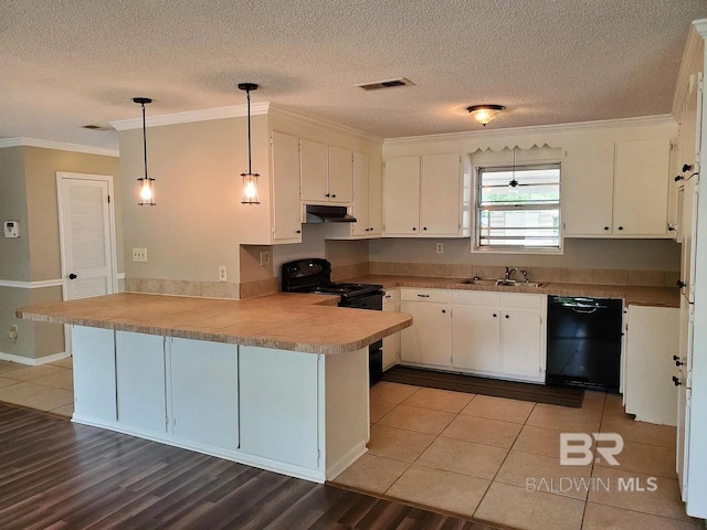 kitchen featuring black appliances, under cabinet range hood, a peninsula, ornamental molding, and white cabinetry