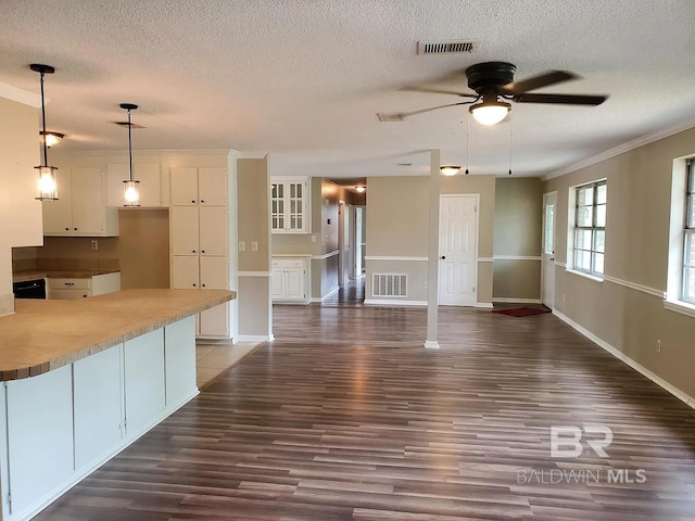 unfurnished living room with a textured ceiling, ceiling fan, wood finished floors, baseboards, and crown molding