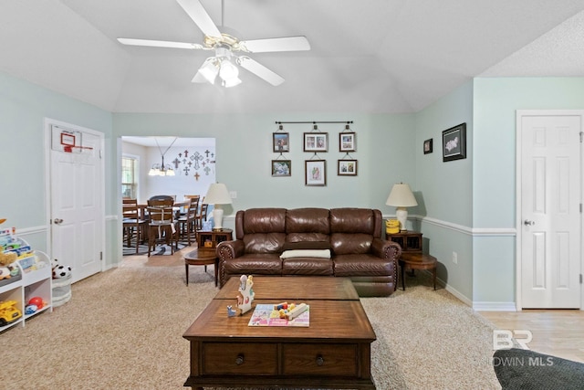 living room with light carpet, ceiling fan with notable chandelier, and vaulted ceiling