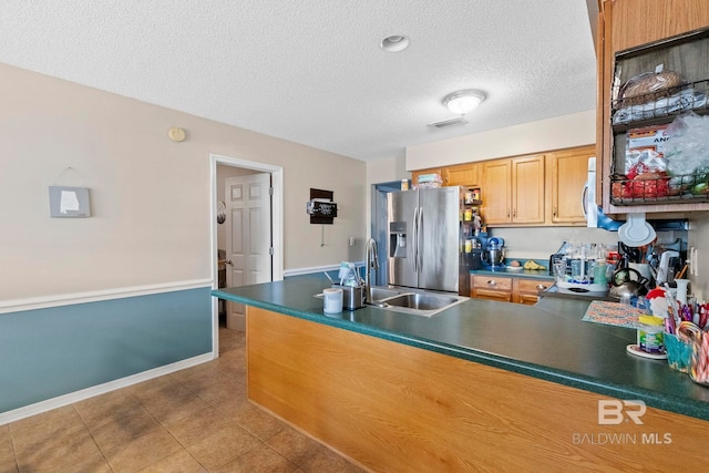 kitchen with a textured ceiling, stainless steel fridge with ice dispenser, and sink