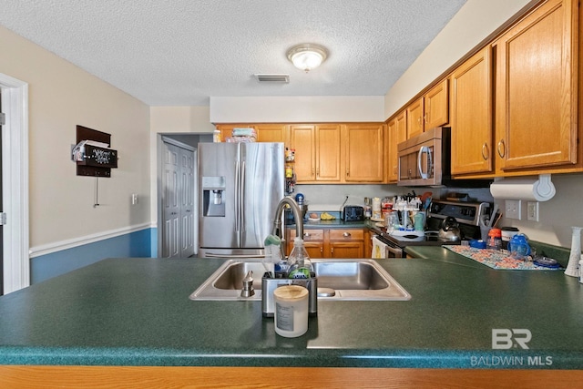 kitchen with a textured ceiling, sink, and stainless steel appliances