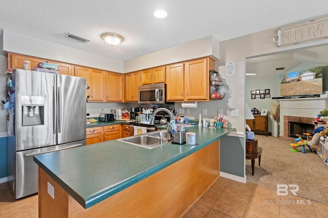 kitchen with kitchen peninsula, light tile patterned floors, a textured ceiling, and stainless steel appliances