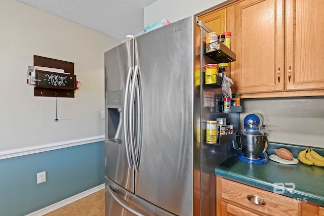 kitchen with stainless steel fridge, light tile patterned flooring, and a textured ceiling