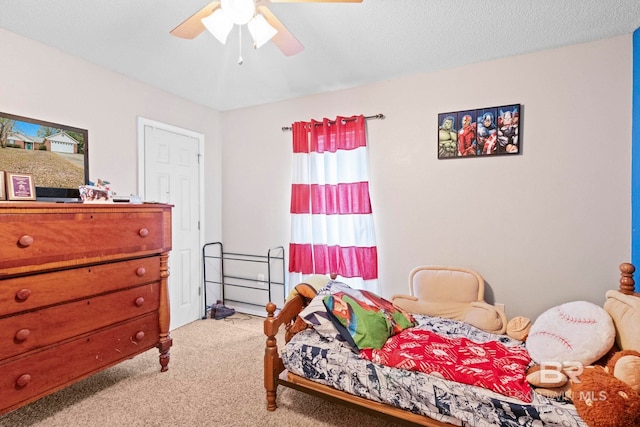 carpeted bedroom with ceiling fan and a textured ceiling