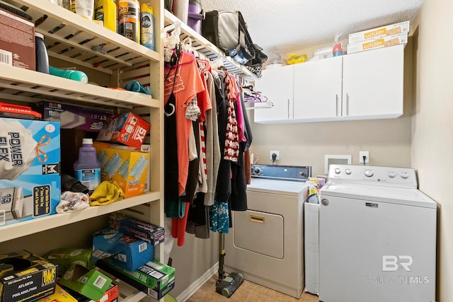 washroom featuring cabinets, washing machine and dryer, and a textured ceiling