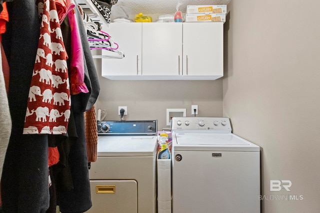 laundry room featuring washing machine and clothes dryer and cabinets