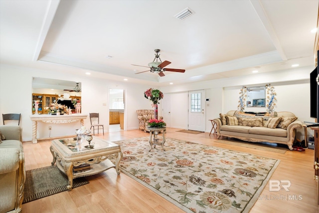 living room featuring ceiling fan, light hardwood / wood-style floors, and a tray ceiling