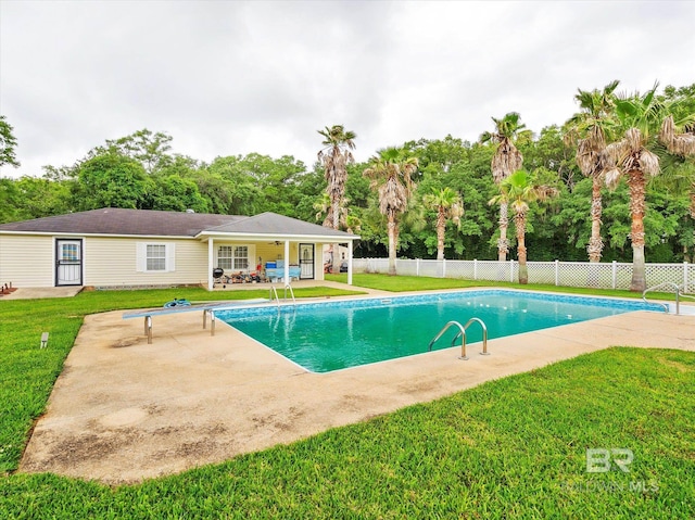 view of pool with a diving board, a patio area, and a lawn