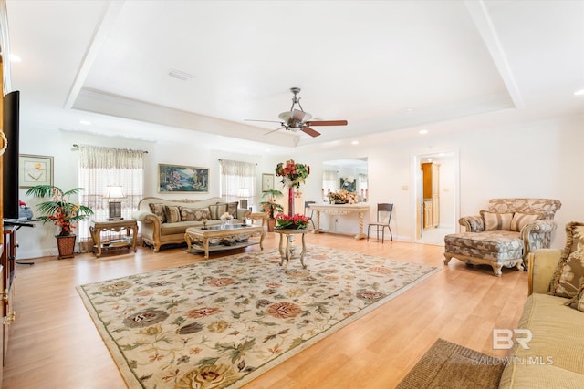 living room with ceiling fan, light hardwood / wood-style floors, and a tray ceiling