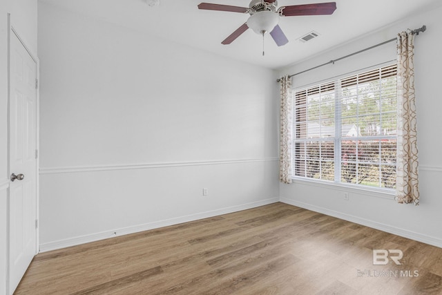 spare room with a ceiling fan, visible vents, baseboards, and wood finished floors