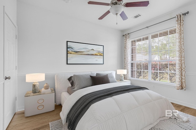 bedroom featuring baseboards, visible vents, ceiling fan, and wood finished floors