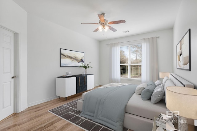 bedroom with baseboards, ceiling fan, visible vents, and light wood-style floors