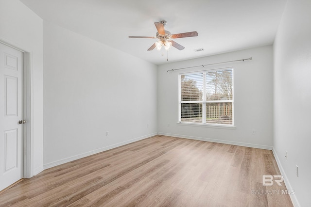 empty room with light wood-style floors, visible vents, and baseboards