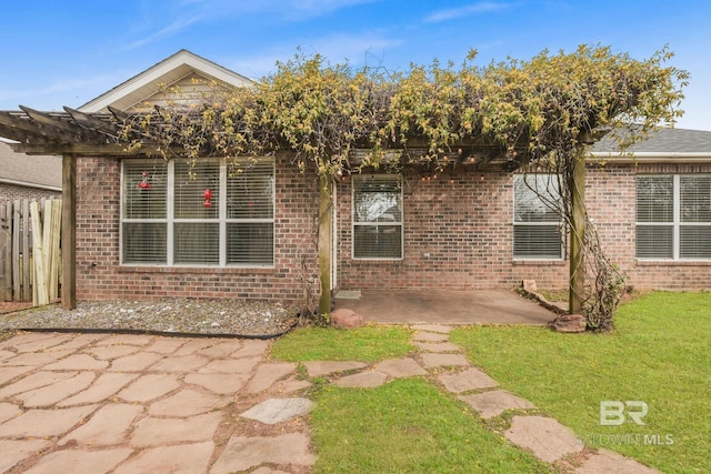 view of front of house featuring a patio area, brick siding, and fence