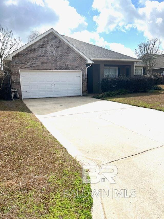 single story home with driveway, brick siding, an attached garage, and a front yard