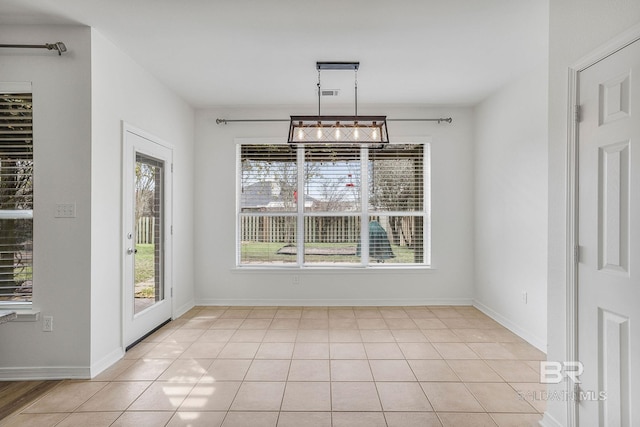 unfurnished dining area with light tile patterned flooring and baseboards