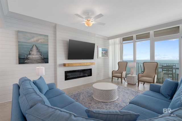 living room featuring wood walls, a large fireplace, and ceiling fan