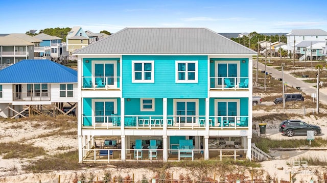 back of house with metal roof, a residential view, and a balcony