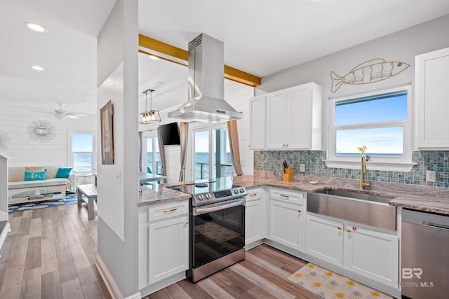 kitchen featuring island exhaust hood, a sink, stainless steel appliances, light wood-style floors, and tasteful backsplash