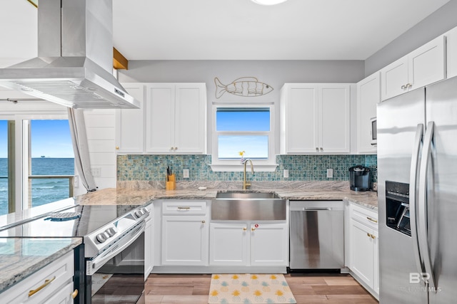 kitchen featuring island exhaust hood, tasteful backsplash, appliances with stainless steel finishes, and a sink