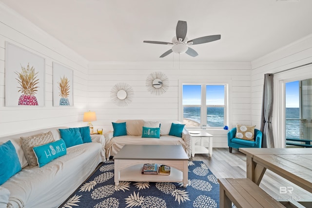 living room featuring a water view, wood finished floors, and a ceiling fan