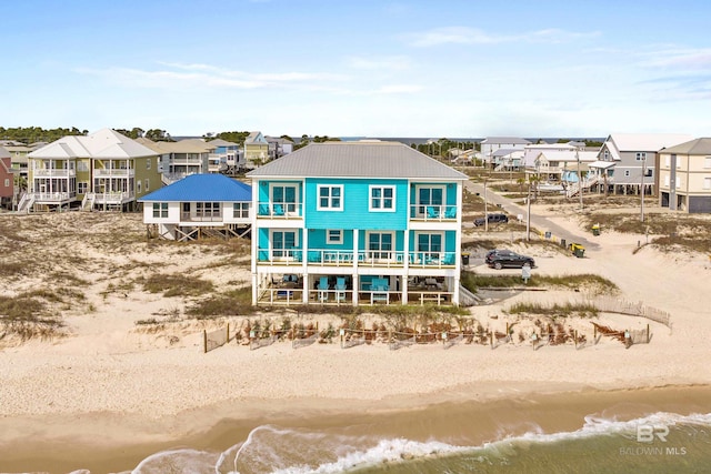 rear view of house with a balcony, a beach view, and a residential view