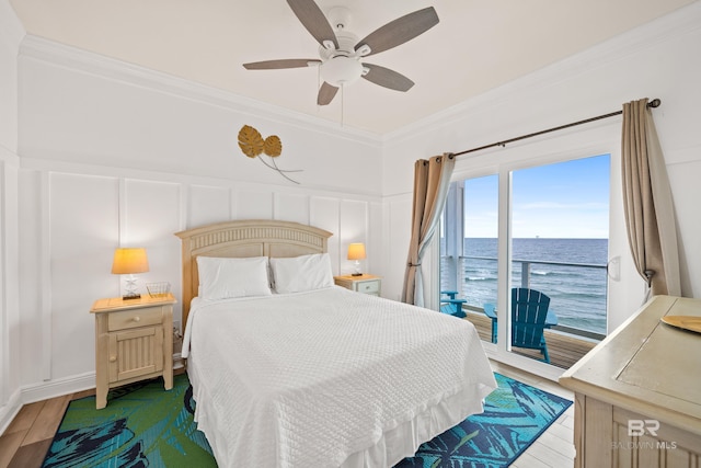 bedroom featuring wood finished floors, access to exterior, crown molding, and a decorative wall