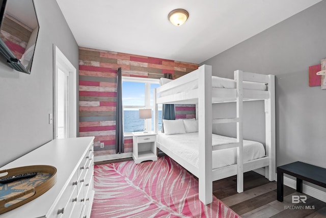 bedroom featuring light wood-style flooring, baseboards, and wood walls