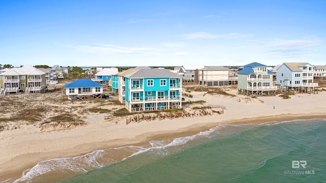 rear view of property featuring dirt driveway, a view of the beach, a residential view, and a water view