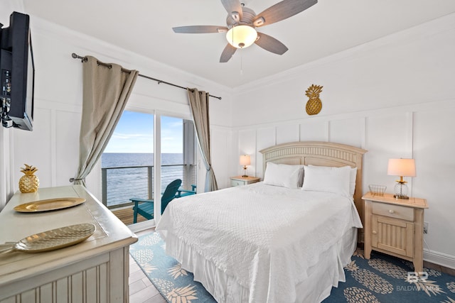 bedroom featuring wood finished floors, access to exterior, crown molding, and a decorative wall