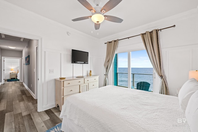 bedroom featuring access to outside, a ceiling fan, wood finished floors, crown molding, and a decorative wall