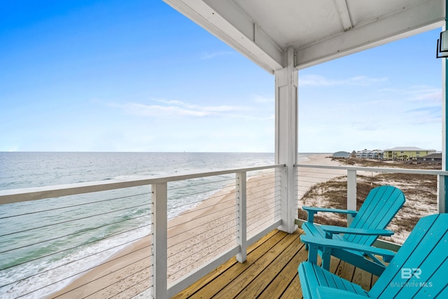 balcony featuring a view of the beach and a water view