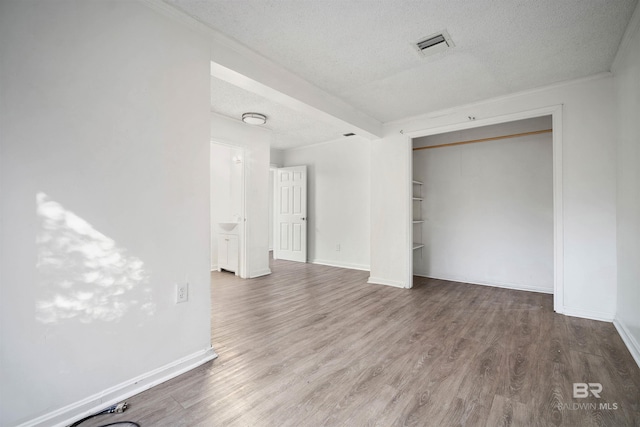 unfurnished bedroom featuring a closet, a textured ceiling, and hardwood / wood-style floors