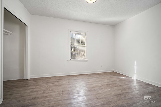 unfurnished bedroom with a closet, hardwood / wood-style floors, and a textured ceiling