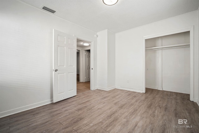 unfurnished bedroom featuring a textured ceiling, wood-type flooring, and a closet