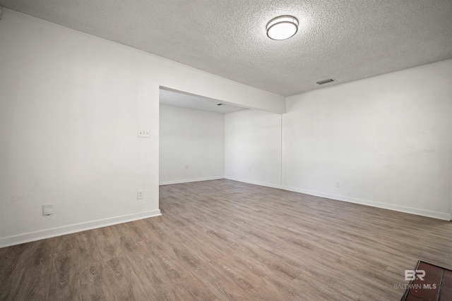 empty room featuring wood-type flooring and a textured ceiling