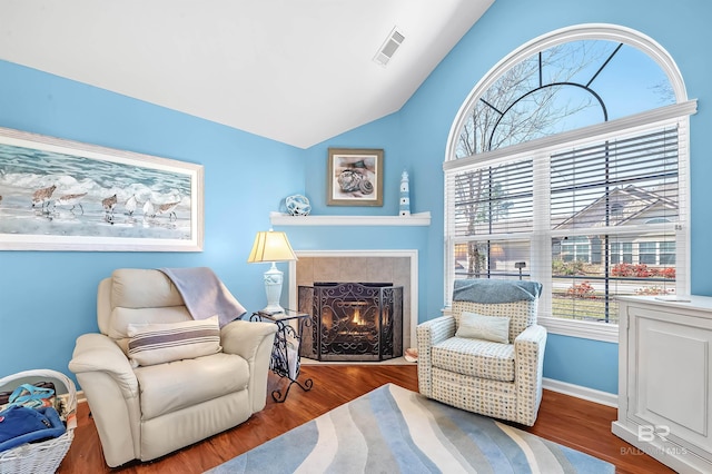 sitting room featuring hardwood / wood-style floors, a tile fireplace, and vaulted ceiling