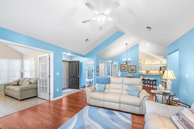 living room featuring vaulted ceiling, light hardwood / wood-style flooring, and ceiling fan with notable chandelier